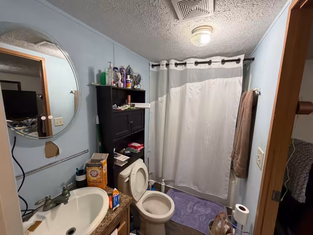 Small bathroom with sink, mirror, toilet, shower curtain, shelf; Arm & Hammer box on counter